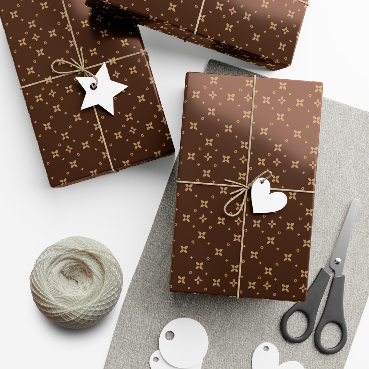 Brown patterned gift wrapped boxes with decorative tags and scissors on a white surface