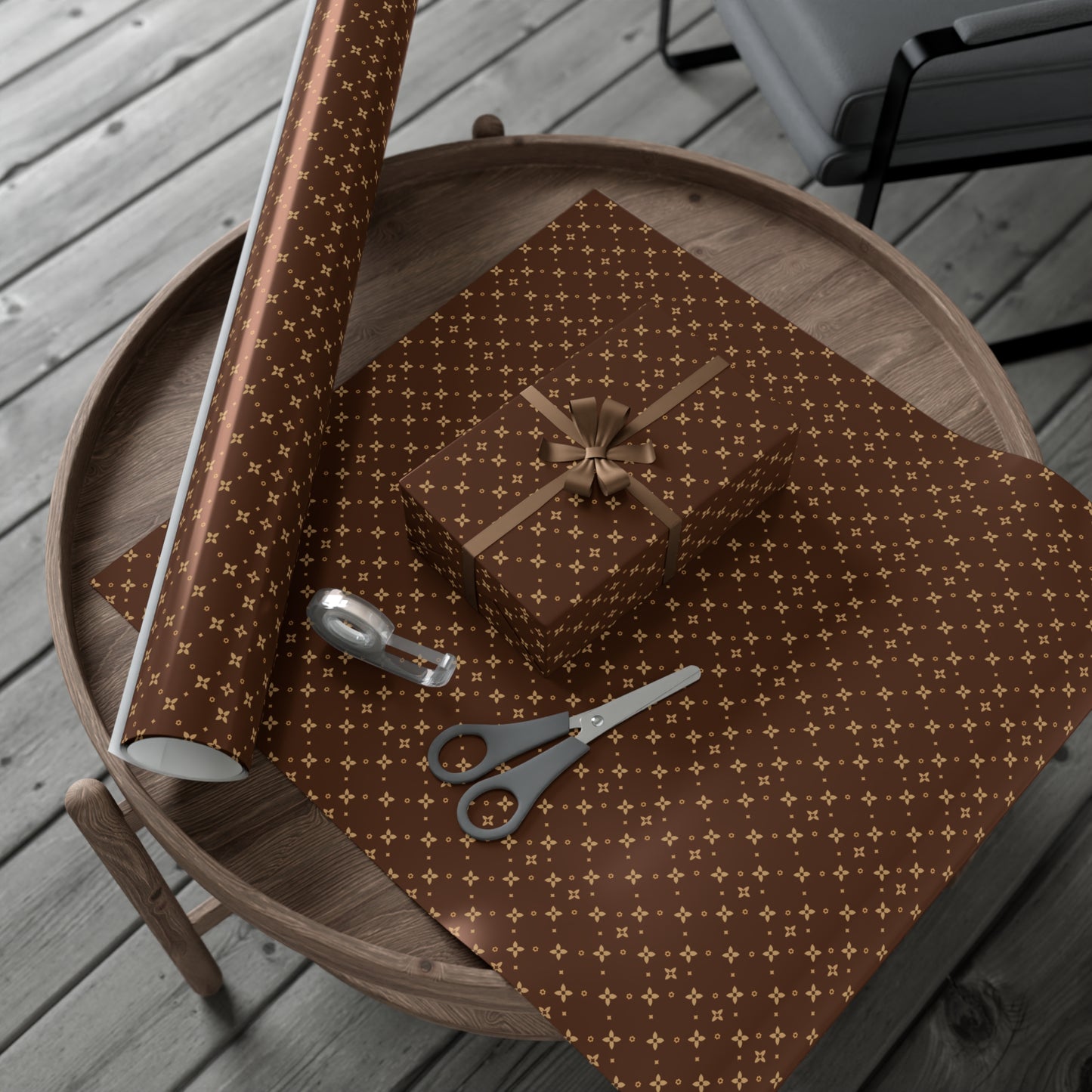 Brown and beige patterned gift wrap on a round wooden table with scissors and tape