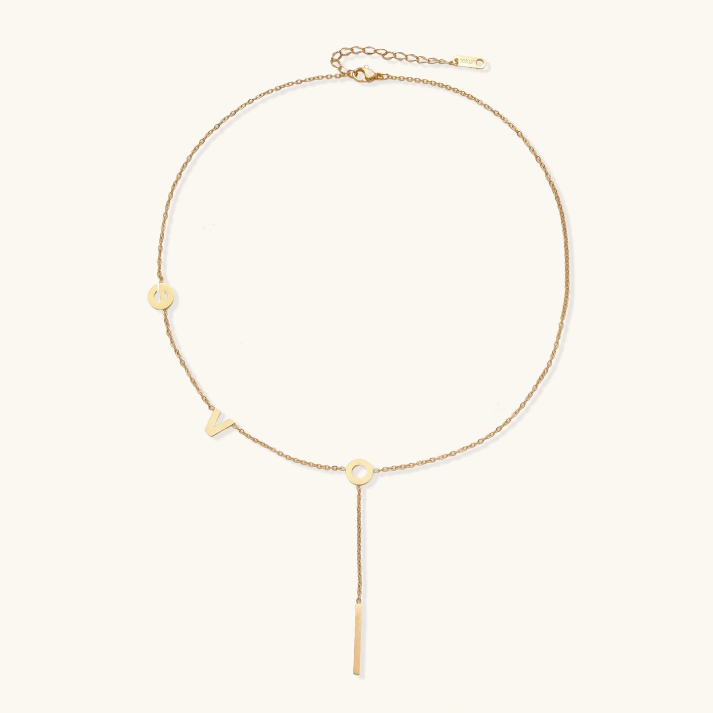 Gold necklace with letters spelling out "love" on a white background