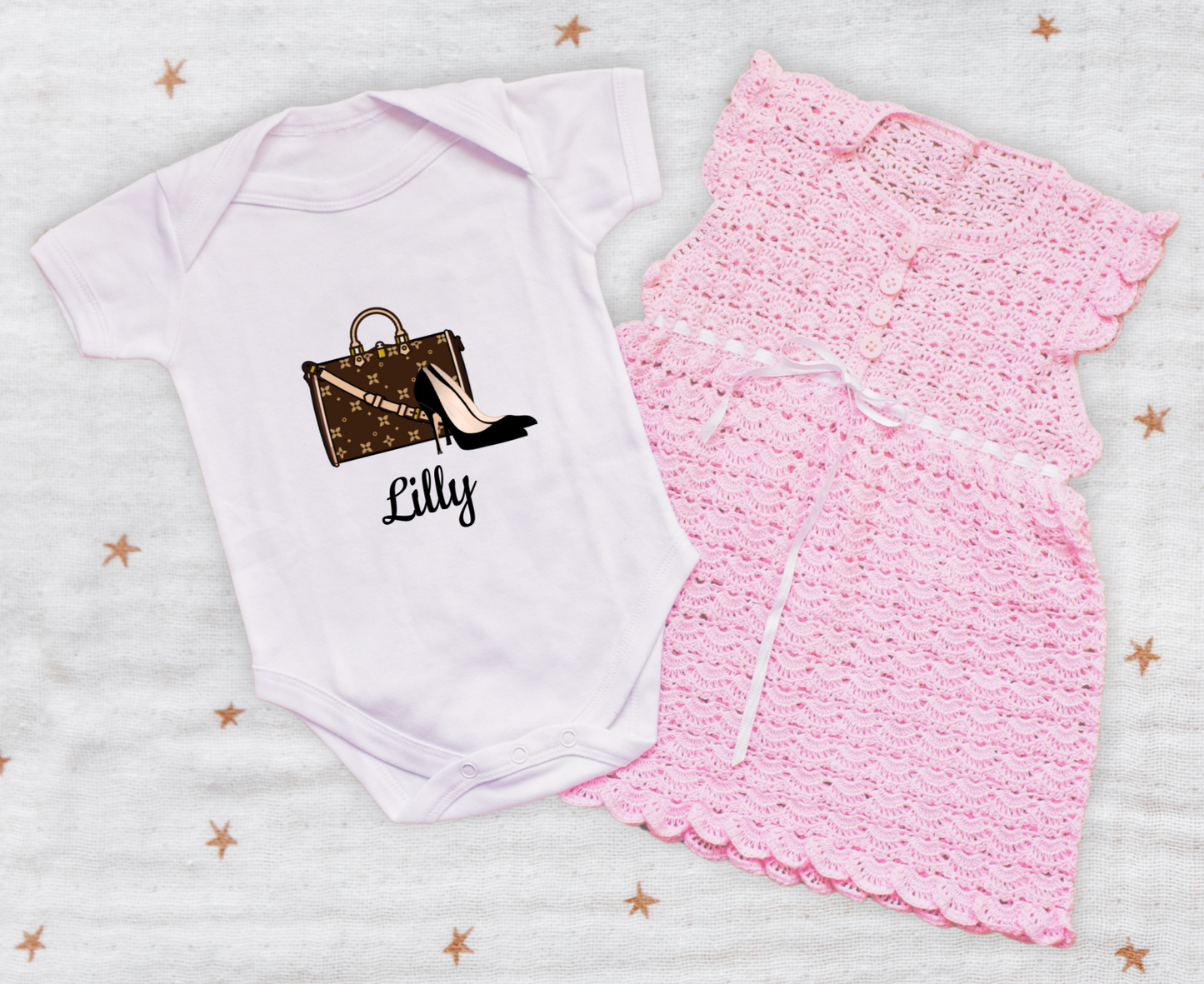 White baby onesie with printed design and pink skirt on a star-patterned background