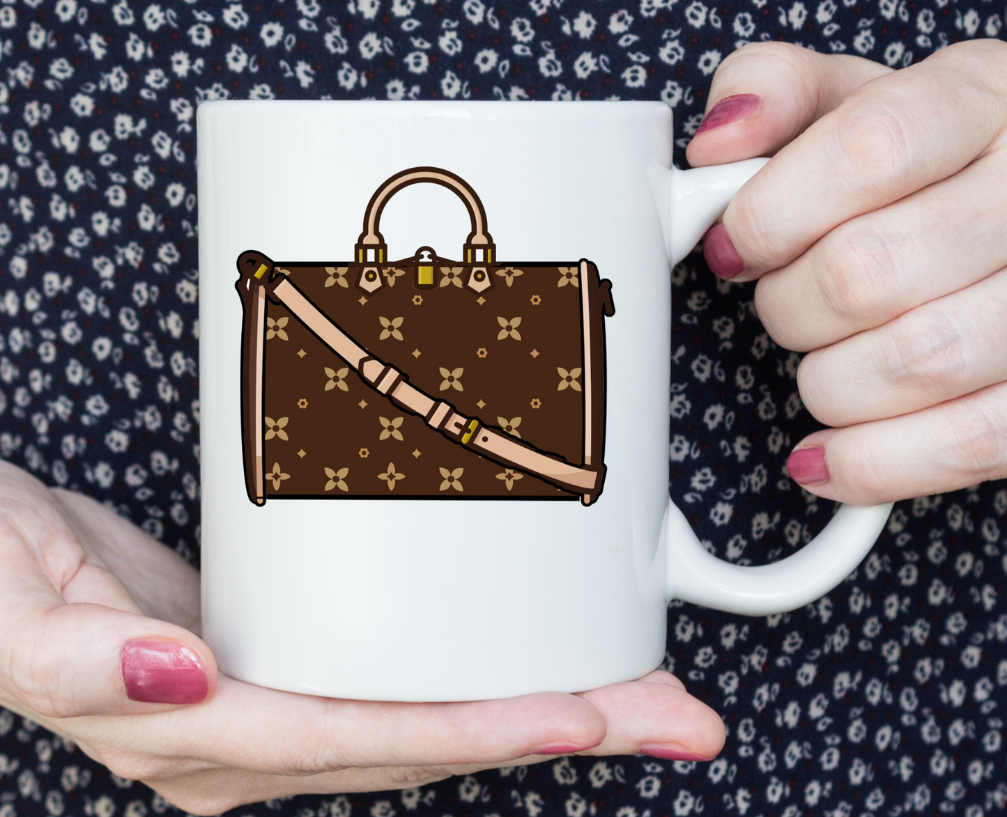 White mug with brown handbag design held by hands against a floral patterned background