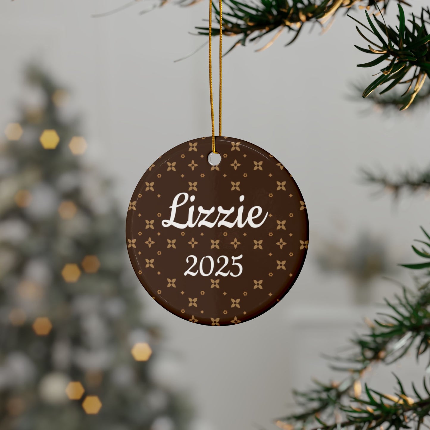 Round decorative ornament with 'Lizzie' and '2025' text, hanging on a tree branch.