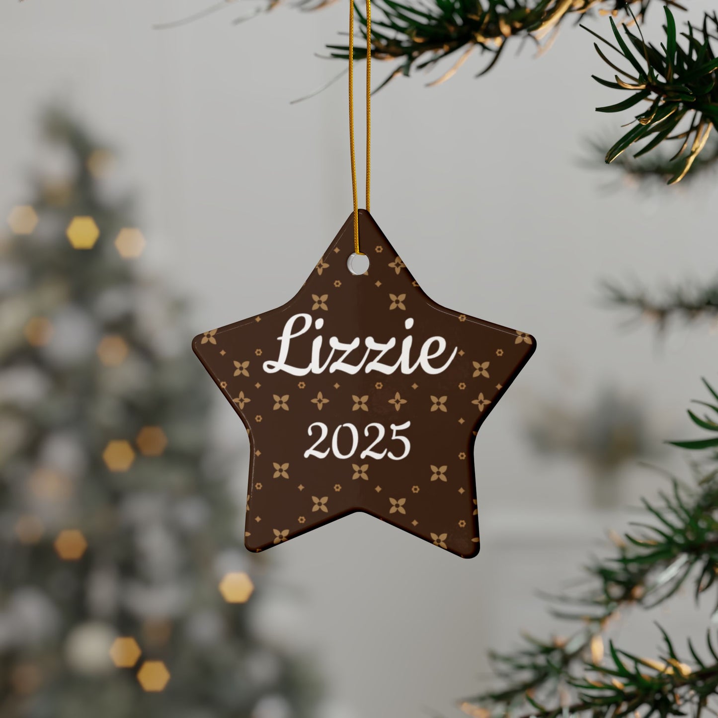 Star-shaped ornament with 'Lizzie' and '2025' text, hanging on a tree branch.