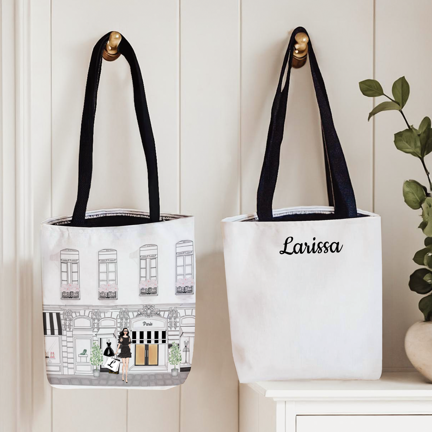 Two tote bags with black handles on a white surface, one featuring an illustration and the other with 'Larissa' text.