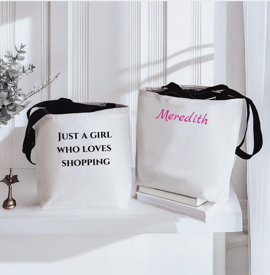 Two white tote bags with text and a name, placed on a white surface.