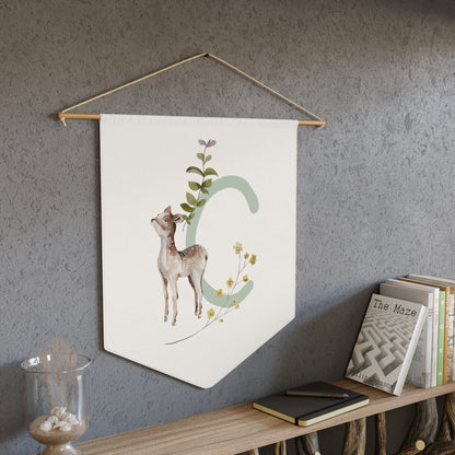 Decorative wall hanging with a deer illustration on a gray wall above a wooden shelf.