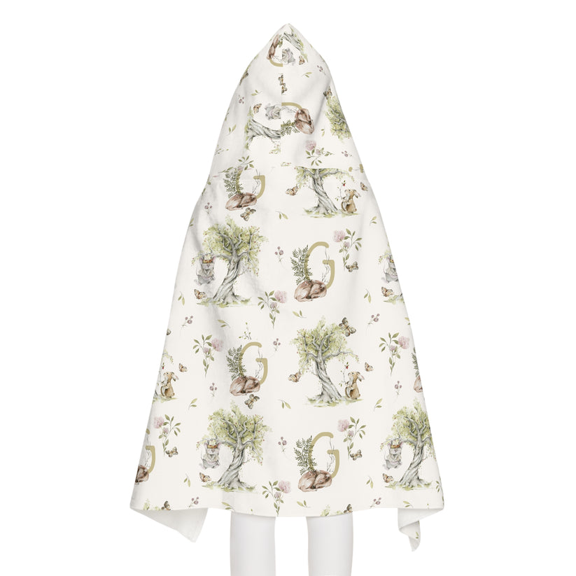 Child wearing a patterned hooded towel with watercolor mice and bunnies and a monogrammed initial in a bathroom