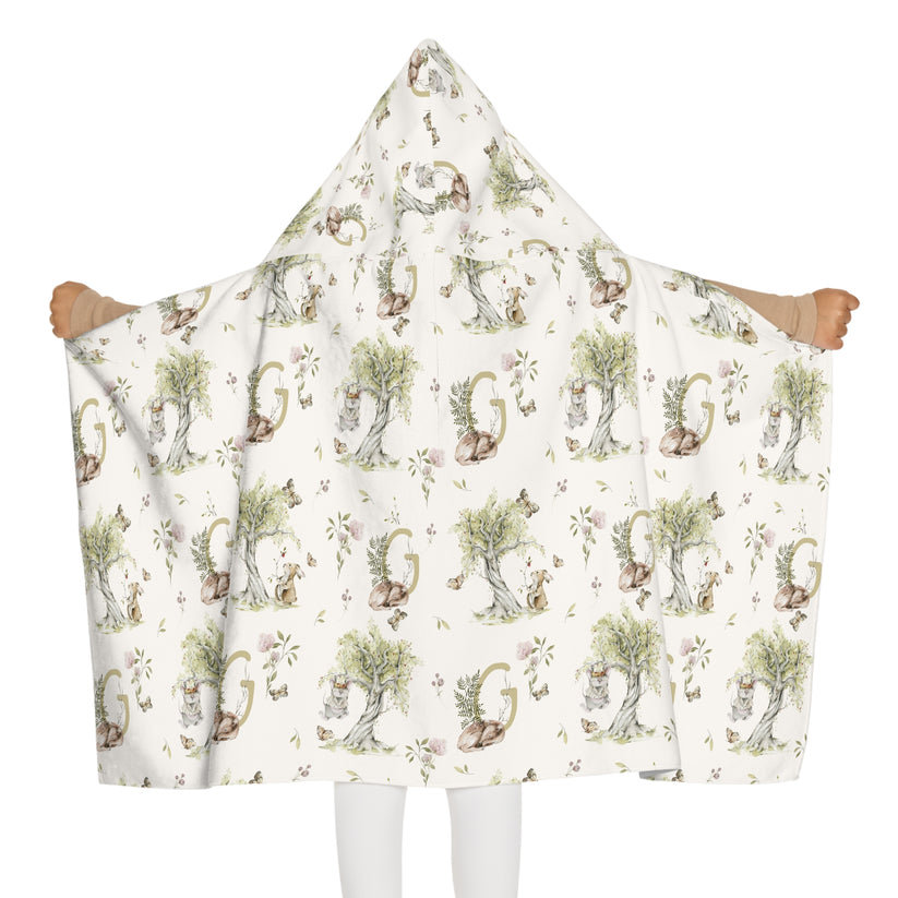 Child wearing a patterned hooded towel with watercolor mice and bunnies and a monogrammed initial in a bathroom