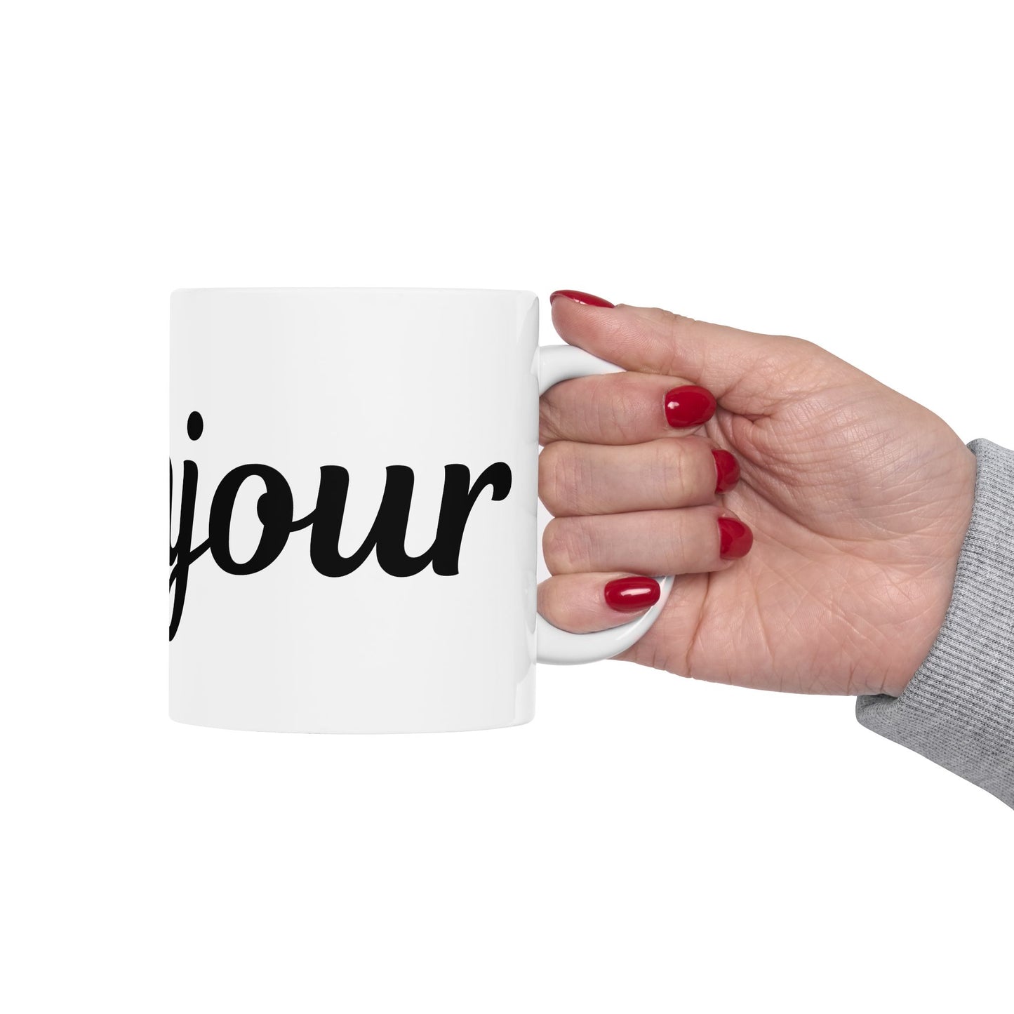 Hand holding a white mug with 'jour' printed on it against a white background
