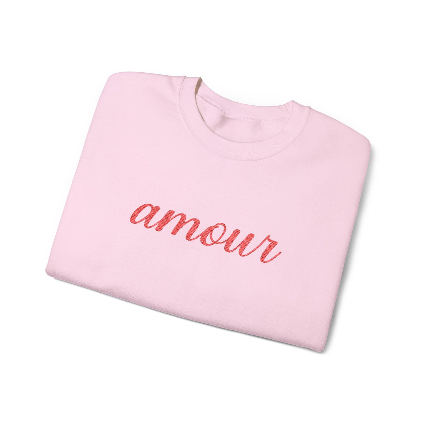 Folded pink sweatshirt with 'amour' text on a white background