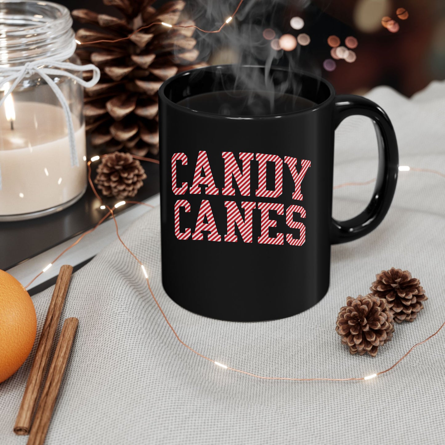 Black mug with 'CANDY CANES' text on a table with festive decorations