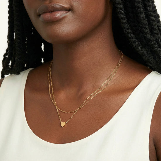 Close-up of a woman wearing a gold necklace with a heart pendant.