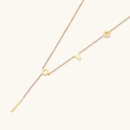 Gold necklace with letters spelling out "love" on a white background