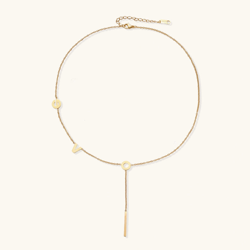 Gold necklace with letters spelling out "love"  on a white background