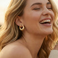 Woman wearing a gold hoop earring with a blurred background
