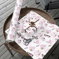 Pink and white fashion theme patterned gift wrap with scissors on a wooden table