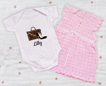 White baby onesie with printed design and pink skirt on a star-patterned background