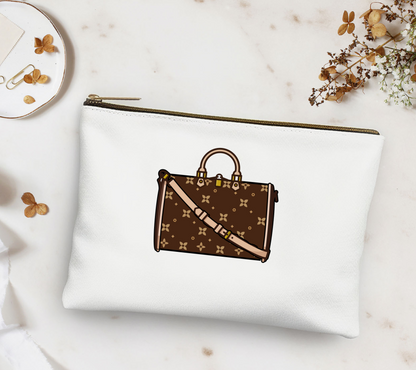 White pouch with brown handbag design on a marble surface with flowers and a plate.