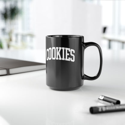 Black mug with 'COOKIES' text on a white surface with office items.
