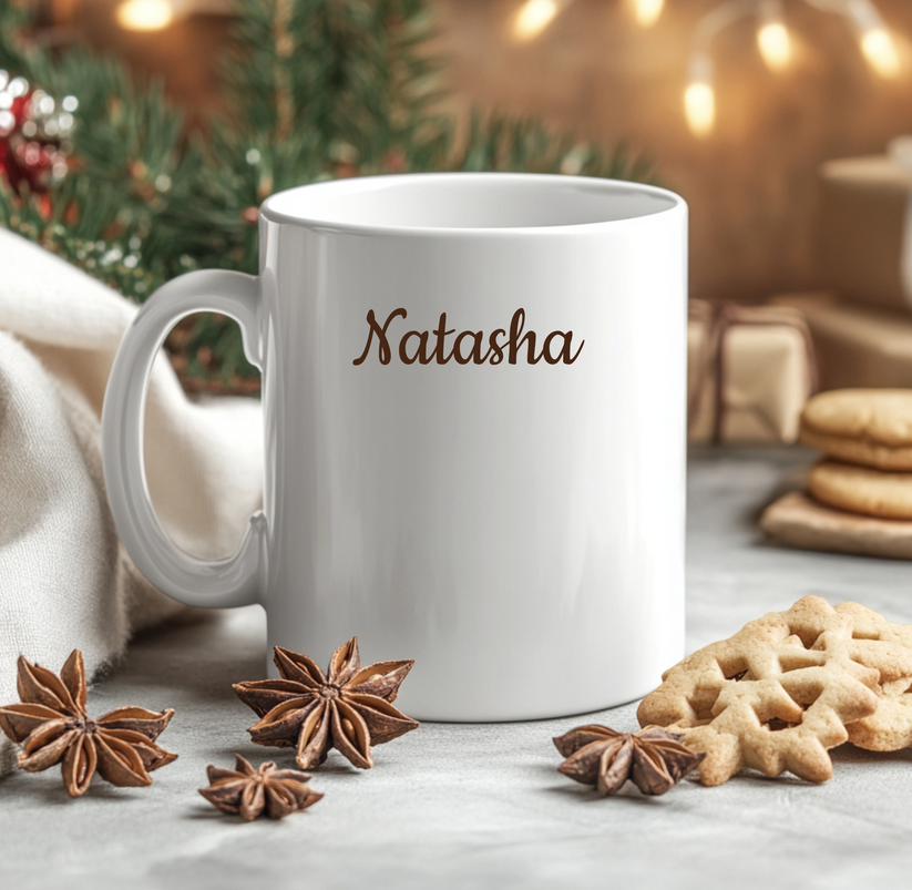 White mug with 'Natasha' printed on it, surrounded by star anise and cookies on a festive background.