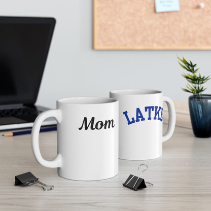 Two white mugs with 'Mom' and 'LATKA' printed on them, placed on a desk with office supplies.