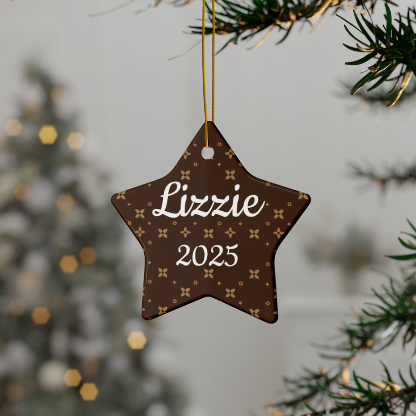 Star-shaped ornament with 'Lizzie' and '2025' text, hanging on a tree branch.