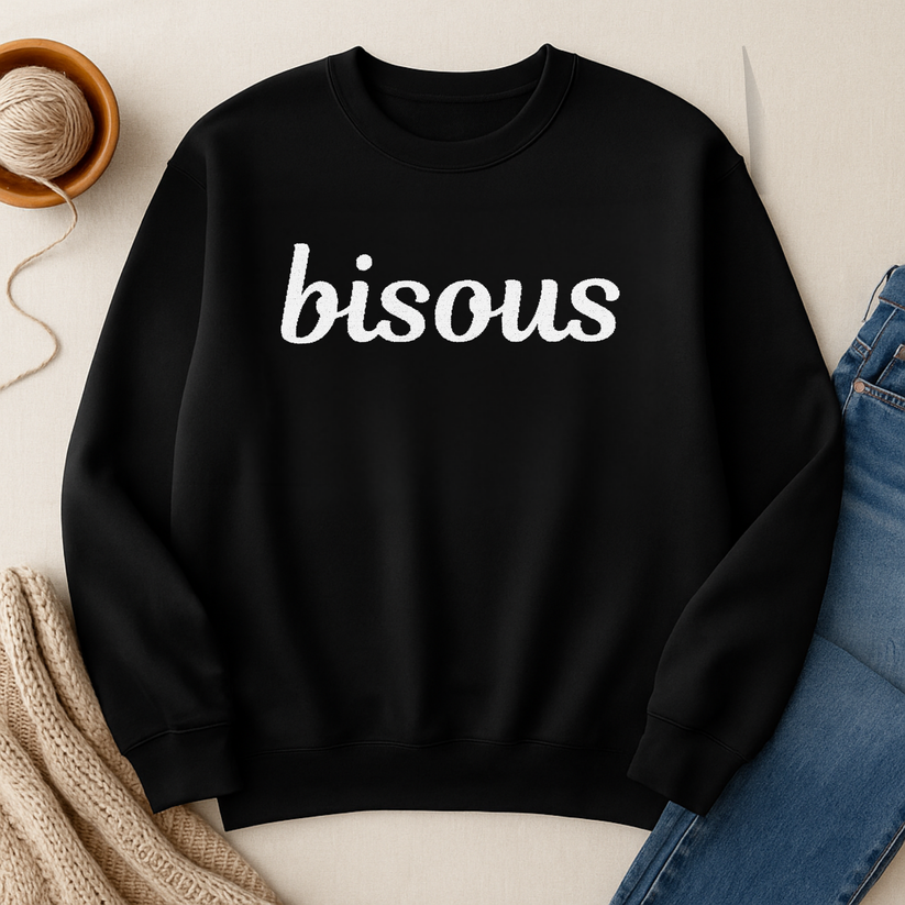 Black sweatshirt with white embroidered 'bisous' text on a neutral background 