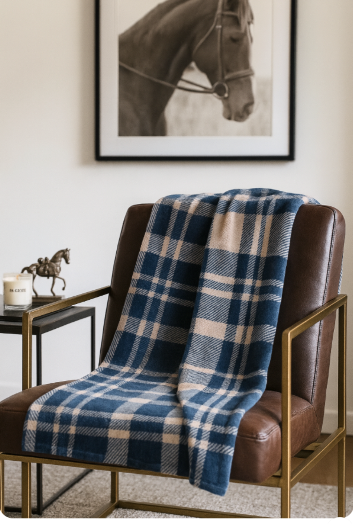 Blue plaid blanket draped over a brown chair in a room with a horse painting on the wall.
