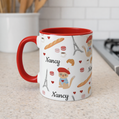 Mug with red handle featuring cat in a red beret surrounded by Parisian items  personalized name on a kitchen counter.