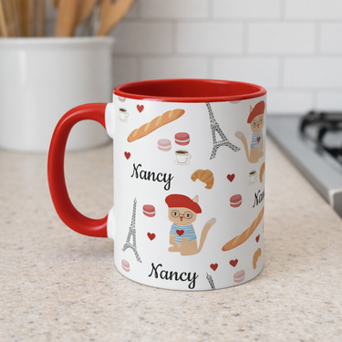 Mug with red handle featuring cat in a red beret surrounded by Parisian items  personalized name on a kitchen counter.