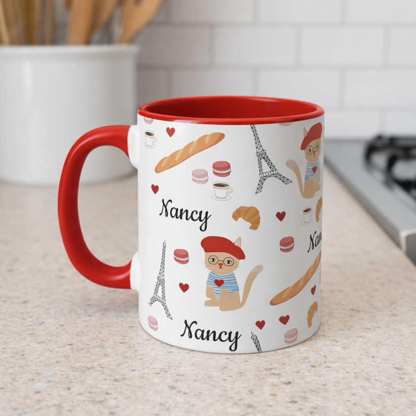 Mug with red handle featuring cat in a red beret surrounded by Parisian items  personalized name on a kitchen counter.