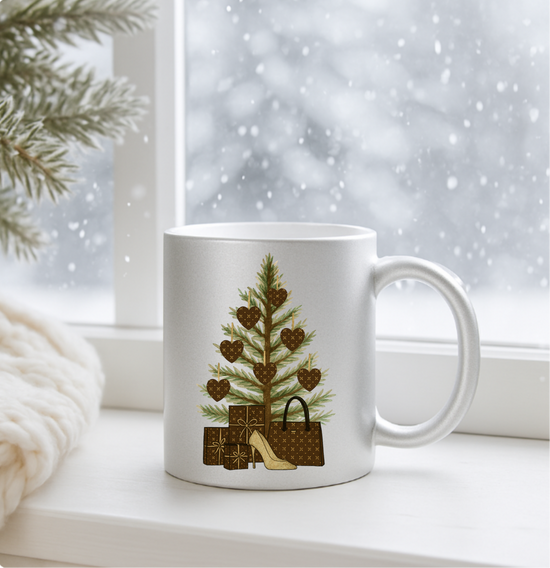 Silver mug with a Christmas tree and gift design on a windowsill with snow outside.