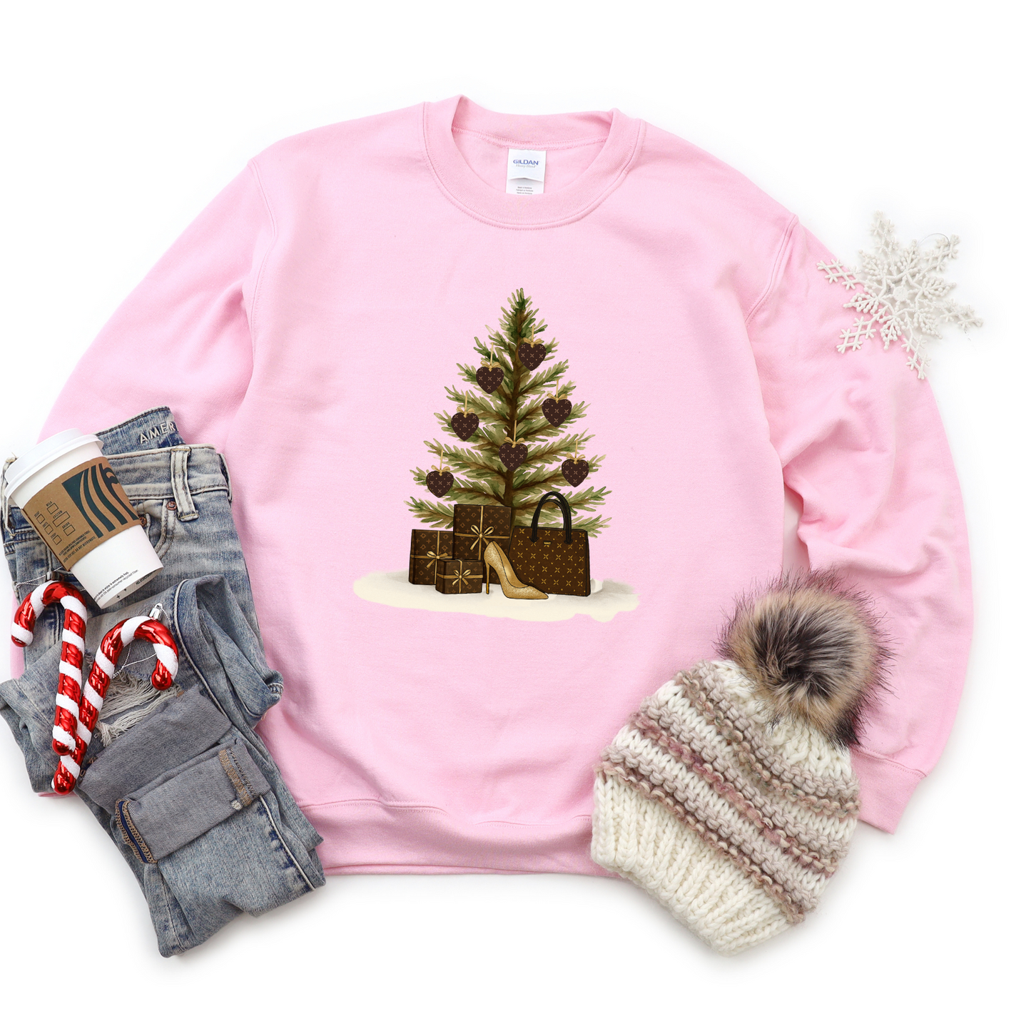 Pink sweatshirt with Christmas tree design, jeans, candy canes, and a hat on a white background