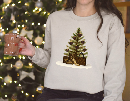 Person wearing a light gray sweatshirt with a Christmas tree and gift design, holding a mug in front of a decorated Christmas tree.