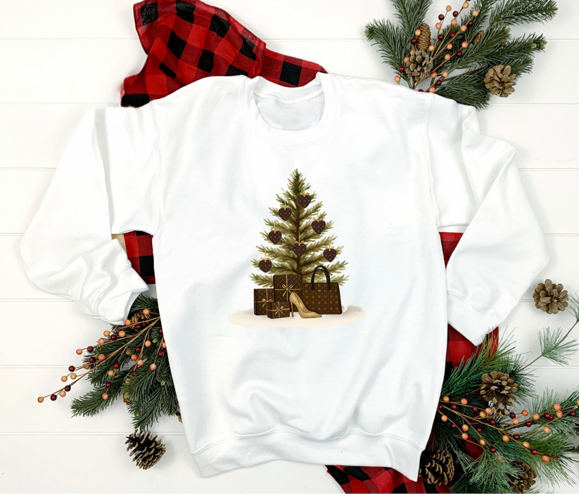 White sweatshirt with Christmas tree and gift design, surrounded by festive decorations on a white background.