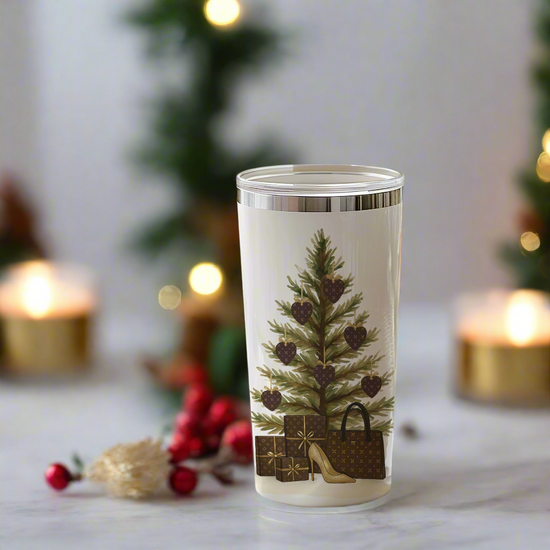 Tumbler with a Christmas tree design on a soft surface with a plant in the background