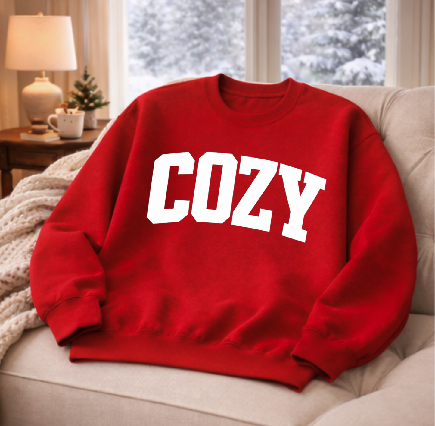 Red sweatshirt with 'COZY' text on a couch in a cozy living room.