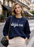 Woman wearing a navy blue sweatshirt with 'déjà vu' embroidered text on a Paris city street.