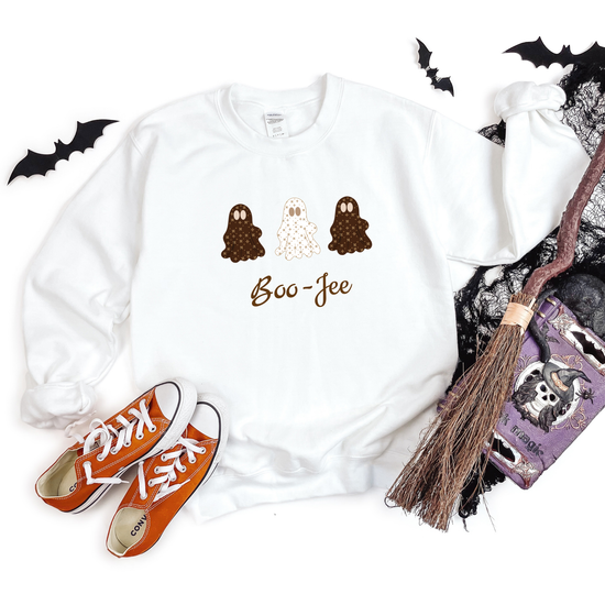 White t-shirt with Halloween-themed design, orange sneakers, broom, and bats on a white background