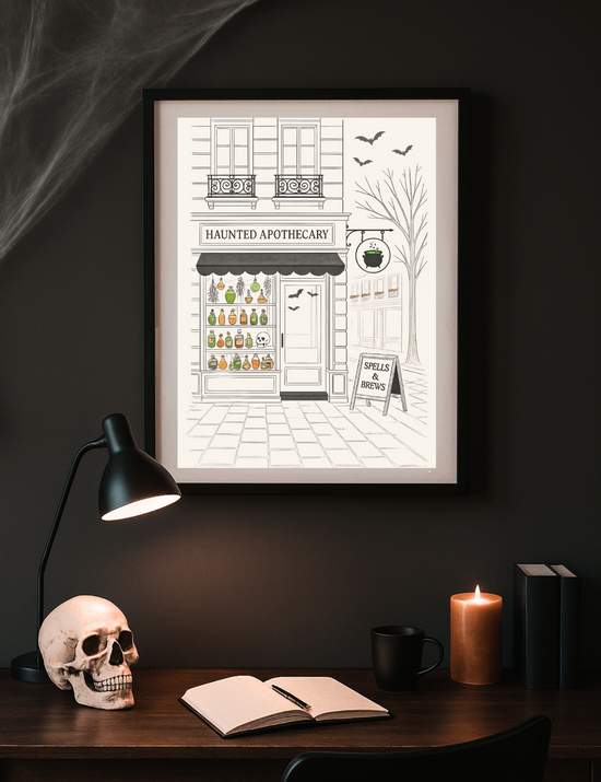 Framed illustration of a haunted apothecary on a dark wall above a desk with a skull, lamp, and books.