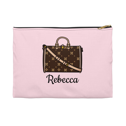 Pink pouch with a brown suitcase design and 'Rebecca' text on a white background