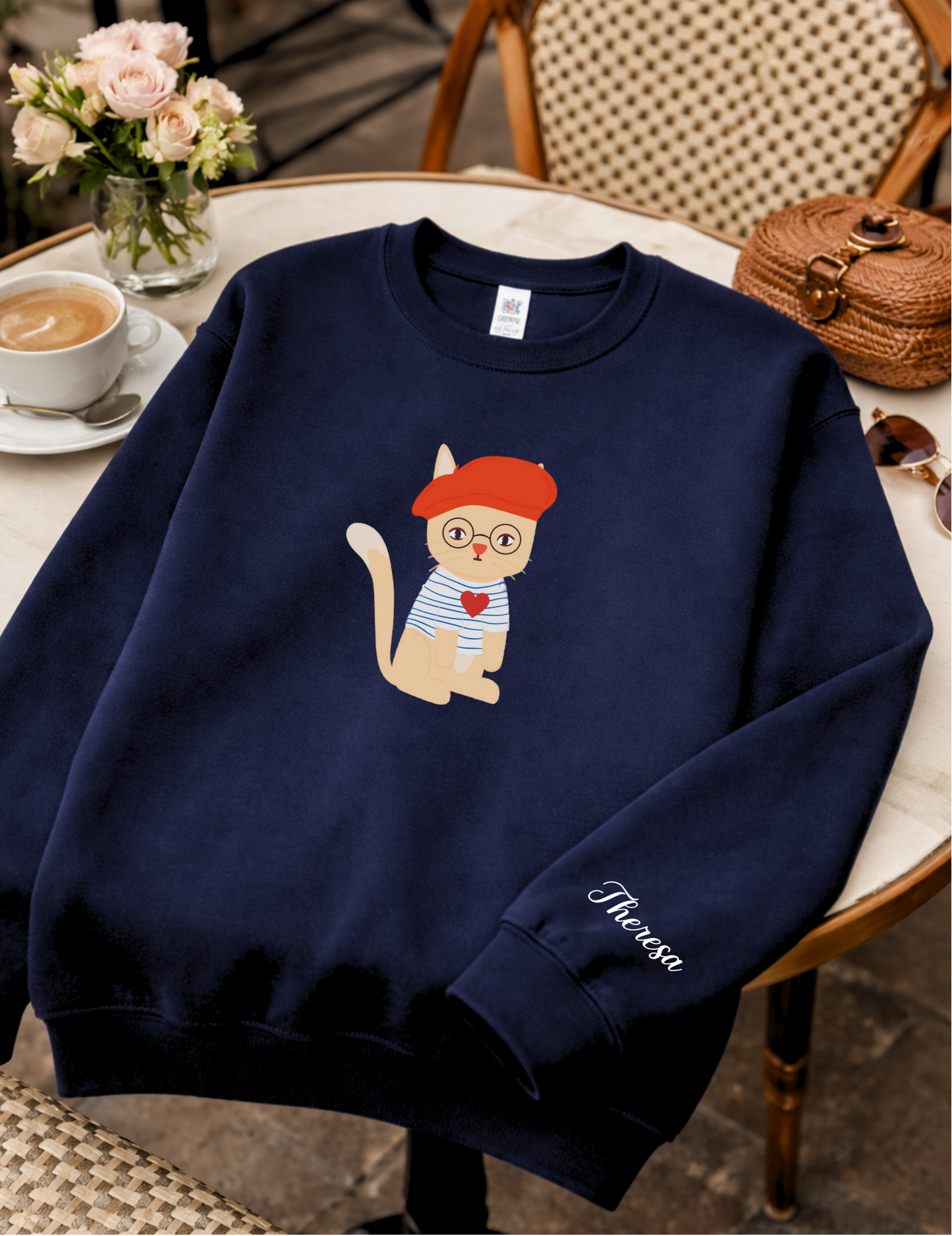 Navy blue sweatshirt with a cartoon cat design on a chair in a cafe setting