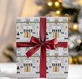 Gift box with festive design and red ribbon against a blurred Christmas tree background