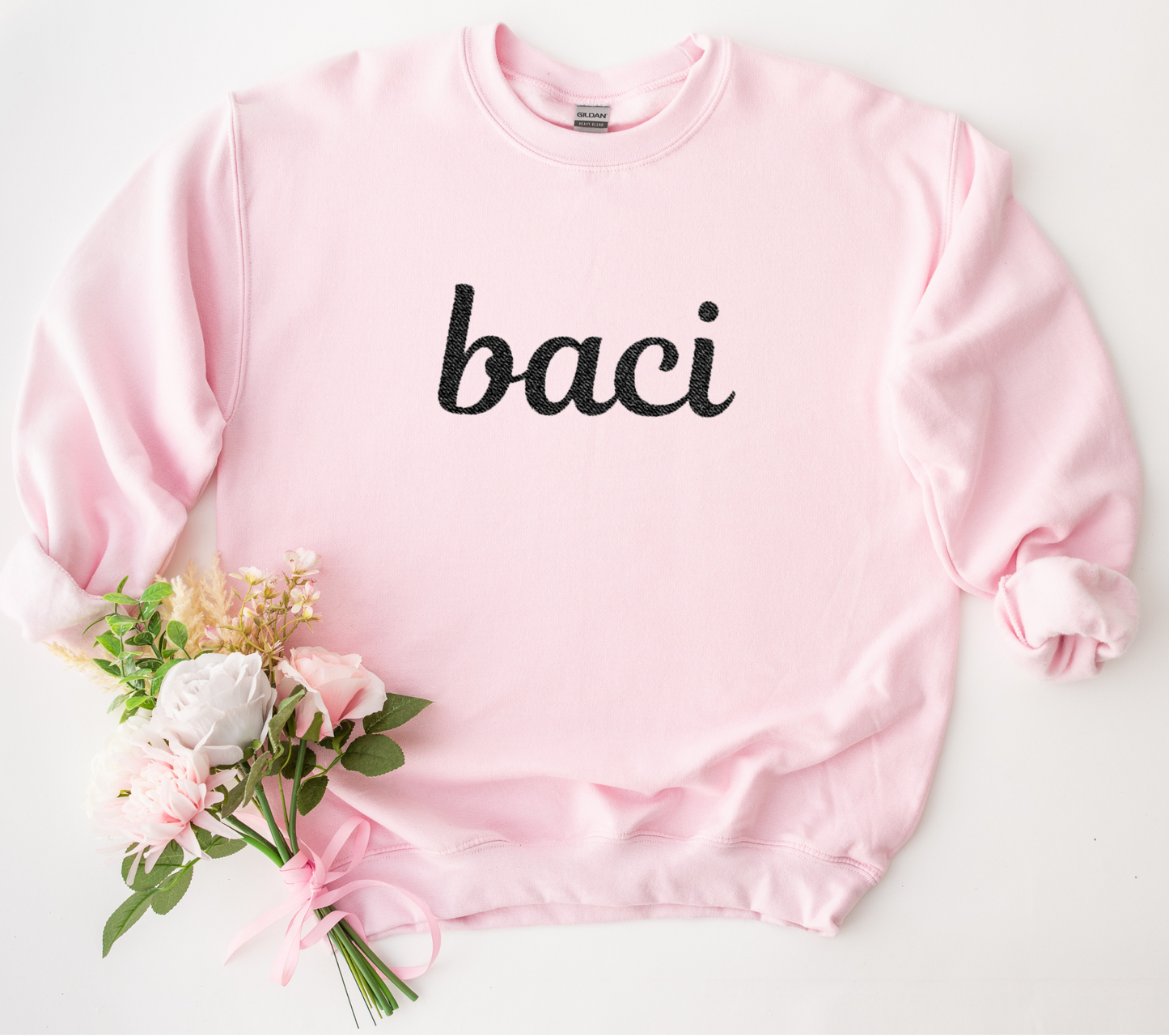 Pink sweatshirt with 'baci' text and flowers on a white background