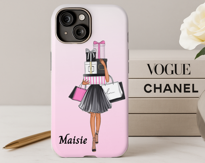 Phone case with a design of a woman holding shopping bags and gifts, placed on a surface with 'Vogue' and 'Chanel' branding in the background.