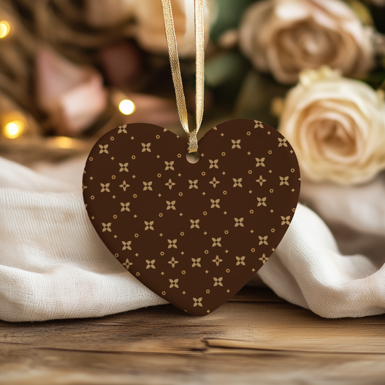 Heart-shaped brown Christmas Ornament with caramel pattern hanging against a blurred floral background