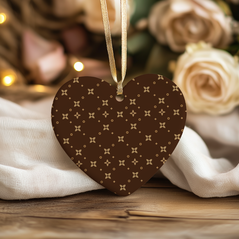 Heart-shaped brown Christmas Ornament with caramel pattern hanging against a blurred floral background