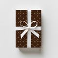 Gift box with brown and beige  pattern and white ribbon on a light gray background
