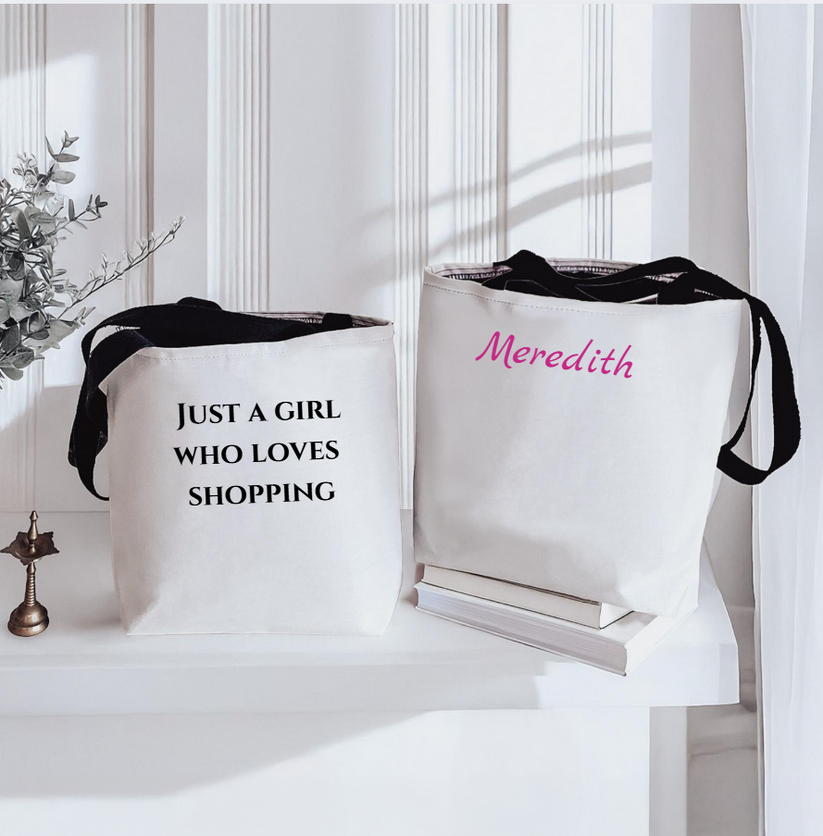 Two white tote bags with text and a name, placed on a white surface.