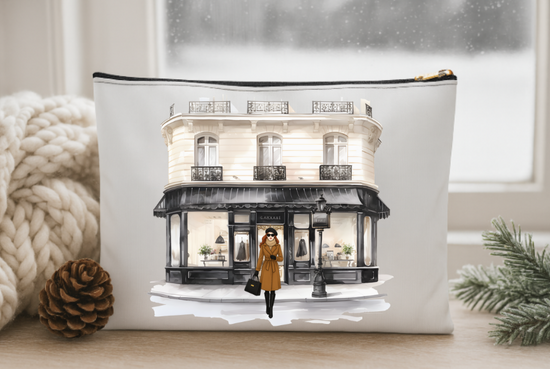 Pouch with a design of a woman in a yellow coat walking past a building on a snowy street.